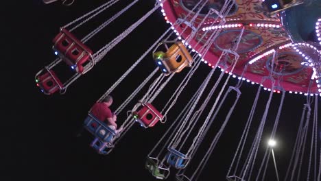 Colorful-carousel-swing-seats-at-night-in-a-park-in-slow-motion