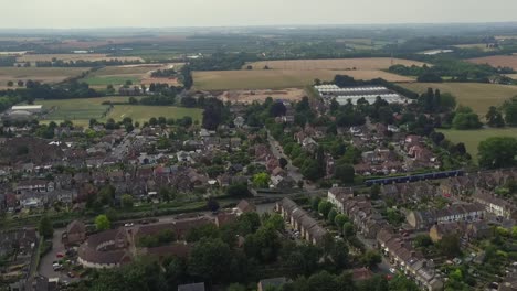Tracking-aerial-shot-of-a-commuter-train-passing-through-the-town-of-Faversham,-Kent,-UK