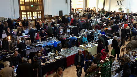 Stallholders-and-customers-in-a-hall-in-Victoria,-London-for-an-antique-fair
