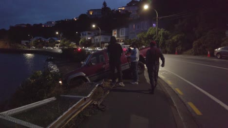 Tilt-up-reveal-showing-car-close-to-crashing-into-ocean,-stopped-by-fence