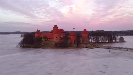 AERIAL:-Drone-Shot-of-Gotic-Style-Medieval-Trakai-Island-Castle-with-Purple-Evening-Light-Color-Casting-From-Sunset