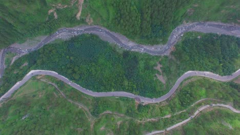 Zigzag-road-top-view,-Kahmir,-India,-Traffice-is-going-on,-Big-forest-and-green-trees,-tow-zigzag-road-and-a-river-view-from-maximum-hieght,-camera-moiving-from-top