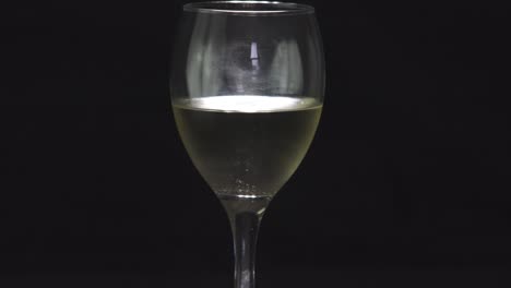 Rotierendes-Glas-Frischer-Weißwein-Auf-Schwarzem-Hintergrund