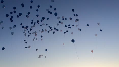 Eine-Große-Gruppe-Von-Menschen,-Die-Bei-Sonnenuntergang-Ballons-In-Die-Luft-Steigen-Lassen