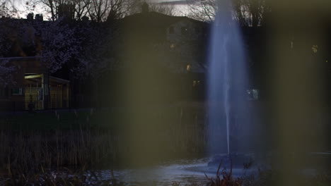 Night-at-the-park,-water-reflection-of-a-fountain-from-a-gate,-urban-paradise