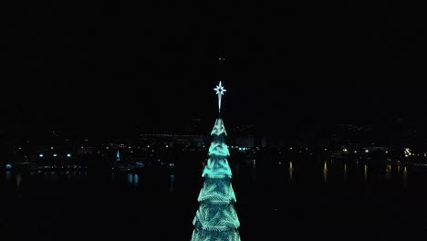 Aerial-circling-around-the-top-of-the-tallest-floating-Christmas-tree-in-the-world-with-changing-lights-in-the-city-lake-of-Rio-de-Janeiro,-Brazil,-2018