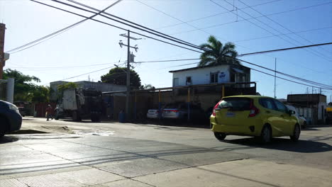 Cars-And-Bike-Taxi-Driving-By-On-A-Downtown-Street-In-Mexico-Past-A-Car-Wash