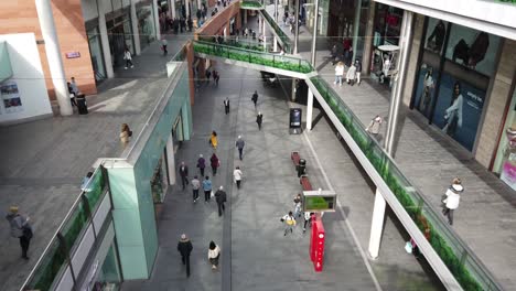 High-angle-perspective-view-down-to-shoppers-in-slow-motion-in-busy-city-shopping-mall,-retail-district