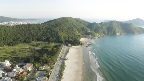 Cinematic-aerial-view-with-a-drone-of-a-beach-with-jungle-mountains-on-a-brazilian-coast,-Bombinhas,-Santa-Catarina,-Brazil