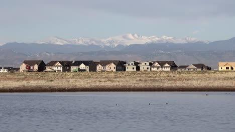 Housing-development-with-lake-in-the-foreground-and-rocky-mountains-in-the-background