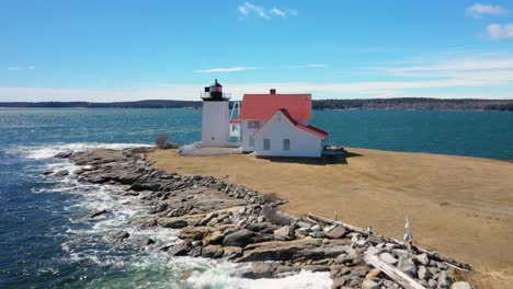 Flying-low-over-Hendricks-Head-Lighthouse-with-waves-crashing-on-penisula-AERIAL