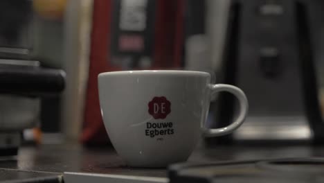 A-Steaming-Cup-of-Douwe-Egberts-Coffee-Being-Placed-Center-Frame