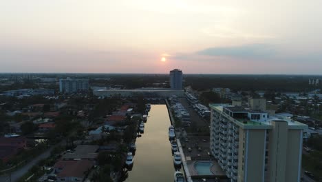 Aerial-video-of-buildings-in-miami-with-the-sunsetting-behind-them,-with-drone-ascending-to-see-better-view-of-sunset