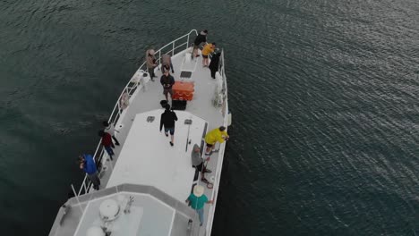 Aerial-flying-over-anchored-cruise-boat-with-people-fishing-on-open-sea-in-New-Zealand