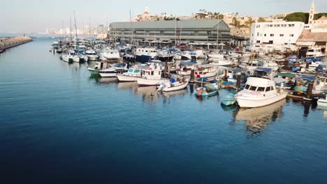 Wunderschöner-Clip,-Der-Zur-Übersichtsaufnahme-Des-Hafens-Von-Jaffa-Mit-Fischerbooten-Und-Booten-Aufsteigt,-Während-In-Der-Ferne-Die-Skyline-Von-Tel-Aviv-Einen-Schönen-Kontrast-Ergibt
