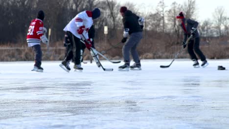 Eine-Weitwinkelaufnahme-Einer-Gruppe-Von-Freunden,-Die-An-Einem-Hellen-Winternachmittag-Teichhockey-Spielen