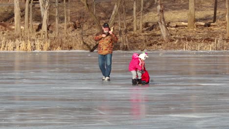 A-grandfather-is-playing-joyfully-with-his-two-younger-nephew-and-niece-on-a-frozen-lake
