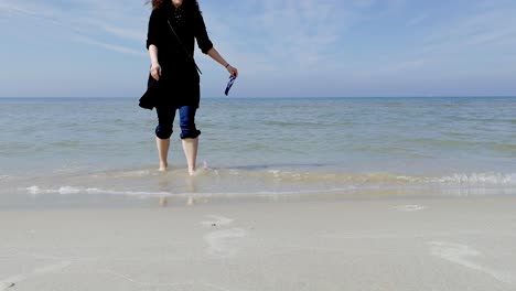 A-wide-shot-of-woman-picks-up-litter-from-the-shore-and-walks-out-of-shot