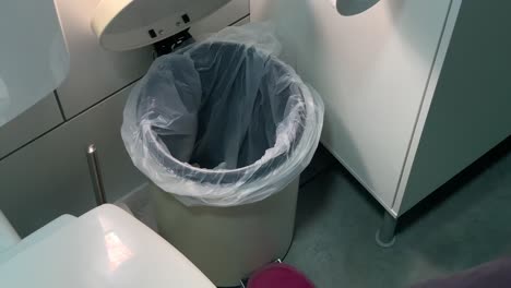 Throwing-handkerchief-trash-into-garbage-in-bathroom