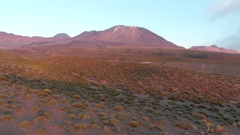Aerial-cinematic-shot-near-the-ground-approaching-a-volcano-at-golden-hour-in-the-Atacama-Desert,-Chile,-South-America