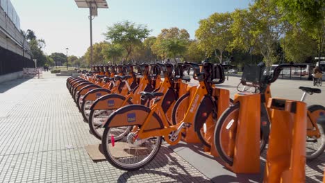 Dolly-In-Orangefarbenen-öffentlichen-Fahrrädern,-Die-Auf-Der-Nachbarstraße-Von-Palermo-In-Buenos-Aires-Geparkt-Sind