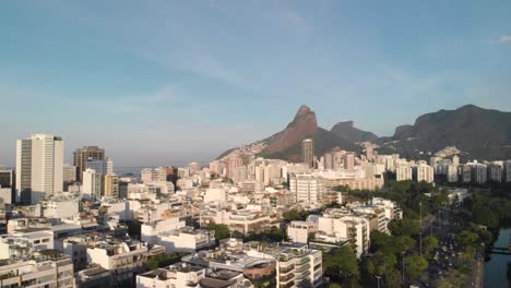 Luftschwenk-Mit-Dem-Berg-Der-Zwei-Brüder-Im-Hintergrund,-Der-Das-Viertel-Ipanema-In-Rio-De-Janeiro-Mit-Hoch--Und-Flachbauten-Bei-Sonnenaufgang-Zeigt
