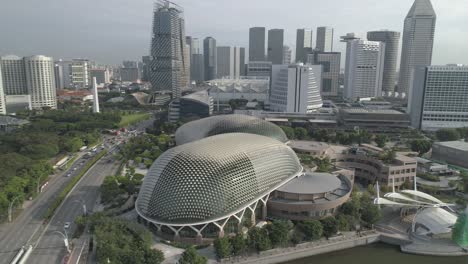 Fliegen-Auf-Das-Berühmte-Esplanade-Theater-In-Singapur,-Während-Der-Autoverkehr-Vorbeizieht-Und-Die-Skyline-Im-Hintergrund-Aufragt