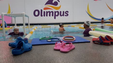 Instructor-fixing-boy's-swimming-googles-at-a-swimming-school