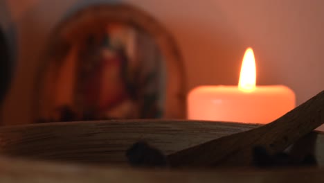 Relaxing-background-detail-shot-of-an-herbal-tea-shop,-with-candles-with-flickering-flames,-herbs,-a-wooden-bowl-and-some-dust-flying-around