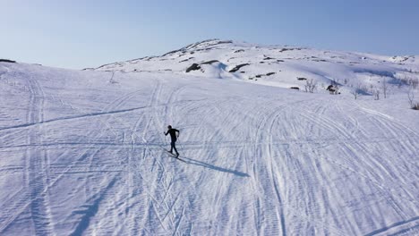 Aerial-view-of-man-on-skis-going-up-snowy-hill