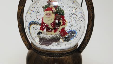Snow-slowly-fall-in-the-glass-Christmas-ball-surrounded-by-white-pattern-in-the-background,-slow-motion