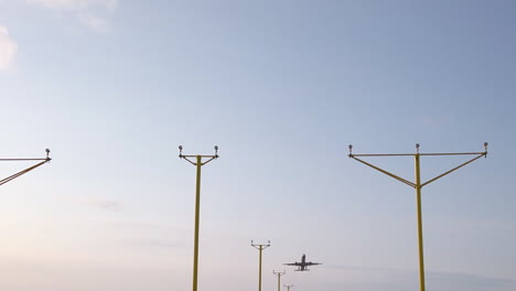 Tiro-Estático-Estrecho-De-Cámara-Lenta-Del-Avión-Que-Sale-Del-Aeropuerto-Internacional-De-Leeds-Bradford-En-Yorkshire-En-La-Hermosa-Mañana-De-Verano-Con-Sistema-De-Iluminación-De-Aproximación-En-Primer-Plano