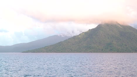 Sunrise-over-a-tropical-volcanic-island-with-clouds-passing-over-mountain-tops-in-sunlight-4k