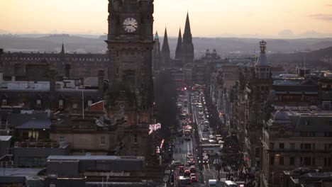Hustle-and-bustle-of-city-life-on-Princes-Street-in-Edinburgh-Scotland-during-blue-hour,-cars-and-trams-drive-on-road