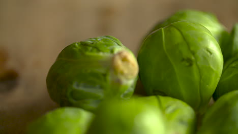 Close-up-of-a-bunch-of-fresh,-green-brussel-sprouts-resting-on-a-wood-cutting-board