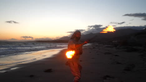 Un-Bailarín-De-Arte-De-Flujo-Masculino-En-Silueta-Interpretando-Su-Fuego-Girando-En-La-Playa-Al-Atardecer-Con-Olas-Oceánicas-En-Cámara-Lenta