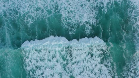Aerial-view-of-breaking-waves-on-the-shore,-shot-from-done-above