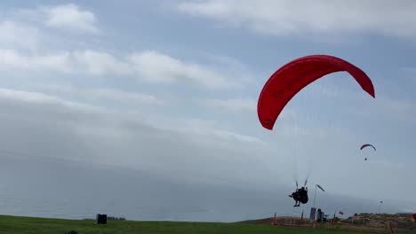 Tandem-paragliders-landing-on-the-ground-of-Torrey-Pines-Glider-Port,-in-La-Jolla