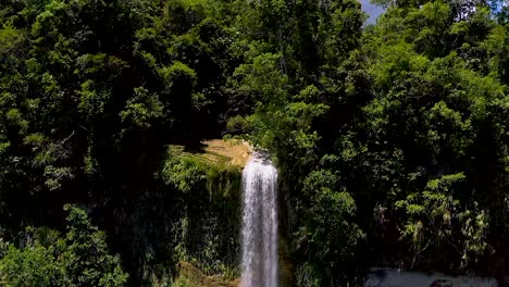 Increasing-altitude-aerial-shot-of-giant-tropical-waterfall-revealing-the-tropical-lush-jungle-in-which-the-waterfall-is-hidden