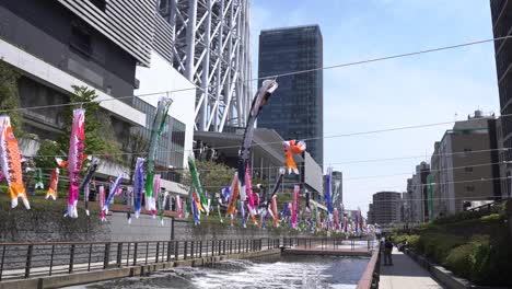 Skytree-of-Tokyo-pan-to-river-with-decorative-Kois-made-out-of-paper,-Japan