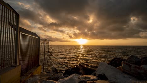 Golden-waves-moving-timelapse-of-sunrise-at-harbor-of-Mitilini---Mytilene-in-Lesvos,-Greece-with-beautiful-clouds-looking-over-the-aegean-sea-in-the-mediterranean,-overlooking-the-Turkish-coast