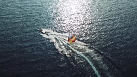 Aerial-shot-of-a-boat-draging-a-parachute-in-the-sea