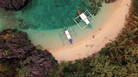 Bird's-eye-view-of-boats-and-tourists-at-the-beach-in-Coron,-Palawan,-Philippines-in-4k