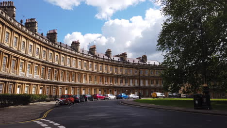 Static-Shot-of-The-Circus-in-Bath,-Somerset-on-Summer’s-Day-with-Blue-Sky---White-Clouds-and-Traffic-Passing-Through-Frame