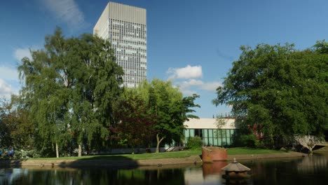 Zeitraffer-Des-Kunstturms-Der-Universität-Von-Sheffield,-Hohes-Gebäude,-Sonniger-Sommertag-Mit-Weston-Park-Davor-Wolken,-Die-Sich-Im-Hintergrund-Bewegen,-Mit-Teich-Davor-Und-Turm,-Umrahmt,-Links-4k-25p