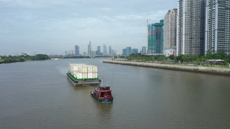 a-tugboat-pulls-a-large-barge-loaded-with-shipping-containers-along-the-Saigon-River