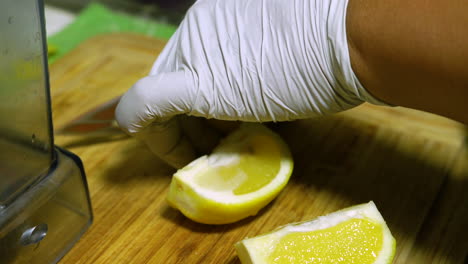 A-person-wearing-white-gloves-is-cutting-a-lemon-on-a-bamboo-cutting-board