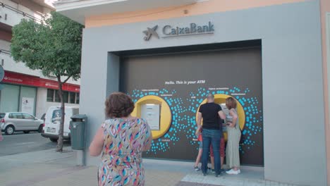 Leute,-Die-Atm-Bei-La-Caixa-Bank-In-Sevilla,-Spanien,-Zeitlupe-Benutzen