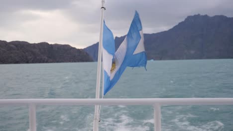 Shot-of-Argentine-flag-in-Argentino-Lake-moving-on-a-boat