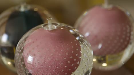 Macro-close-up-shot-of-three-glossy-decorative-glass-balls-on-top-of-a-wooden-table